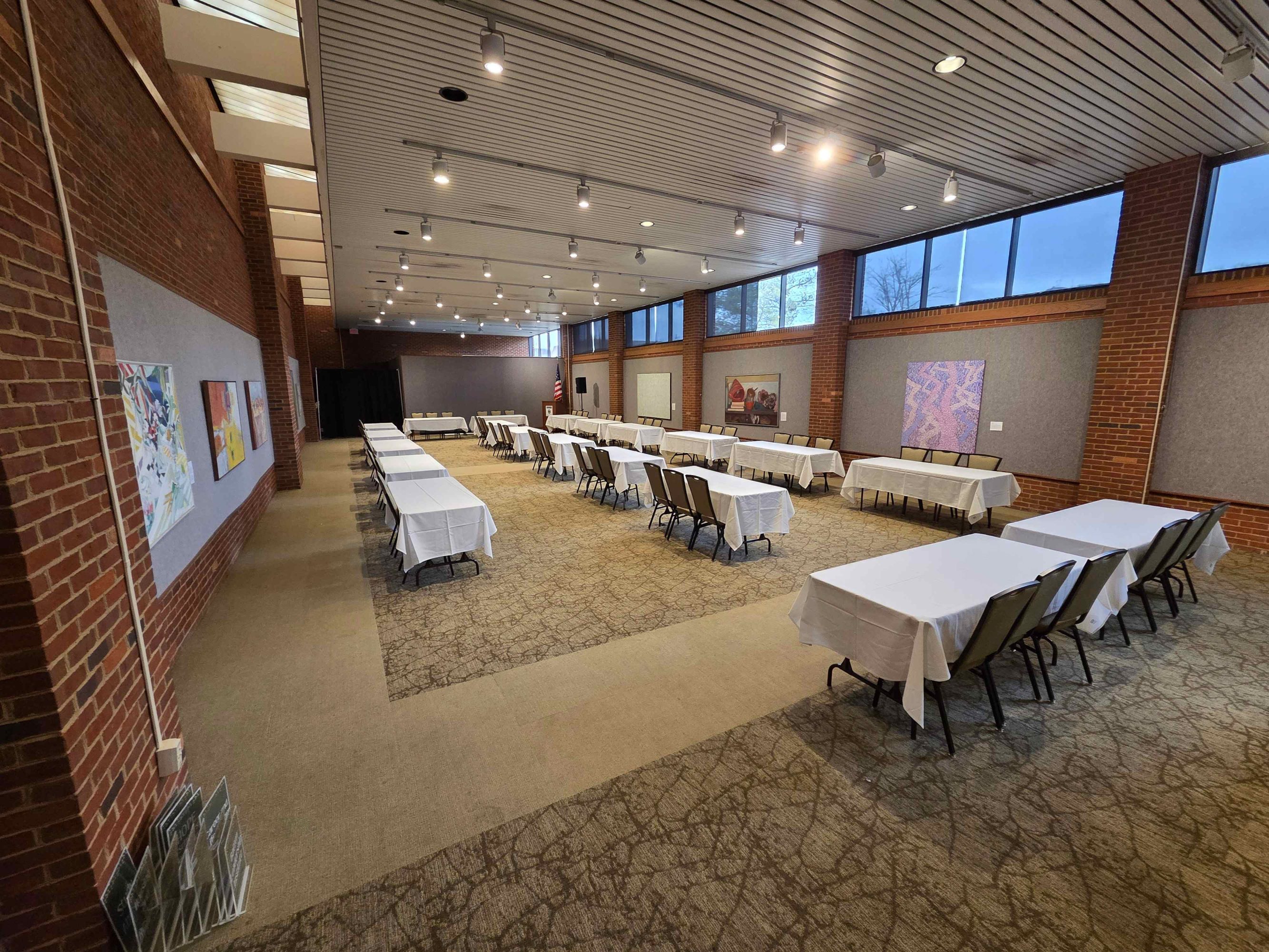 A large open room with several 6ft long tables with chairs and table cloths