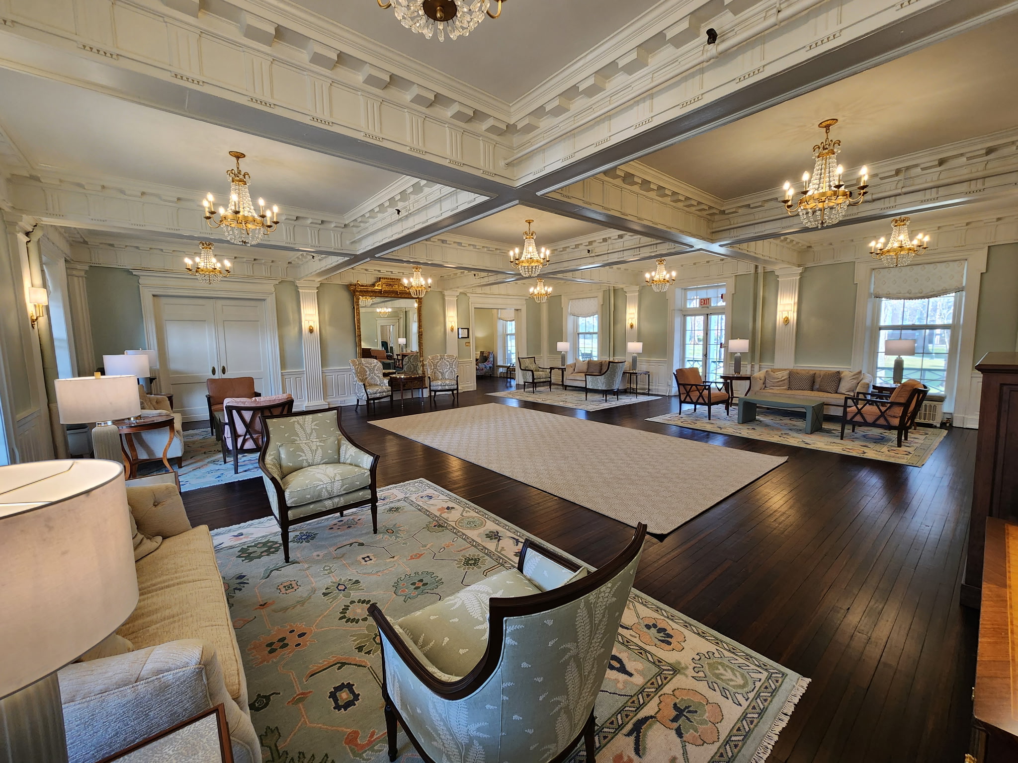 A lounge space with light green walls and empty seating chairs