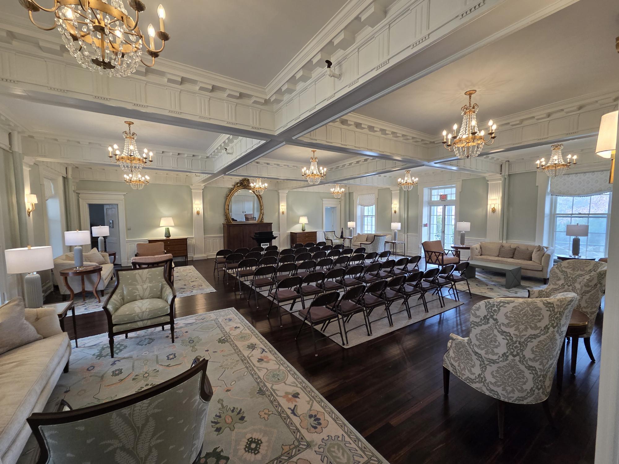 Image of a green room with rows in chairs facing a mirror and podium
